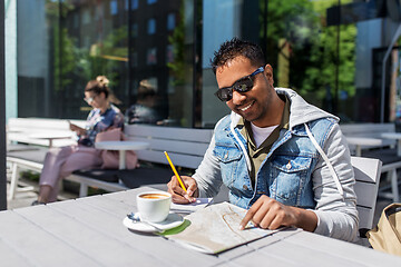 Image showing man with map and notebook at street cafe in city