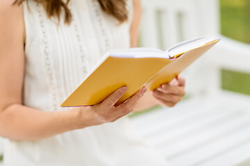 Image showing close up of young woman reading book at park