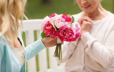 Image showing daughter giving flowers to senior mother at park