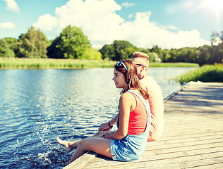 Image showing happy teenage couple sitting on river berth