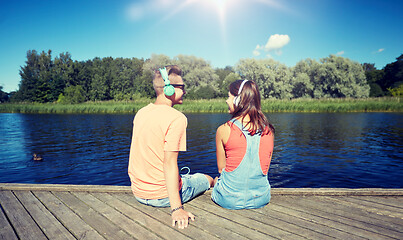 Image showing teenage couple with headphones on river berth