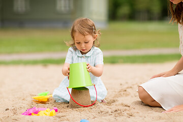 Image showing little baby girl plays with toys in sandbox