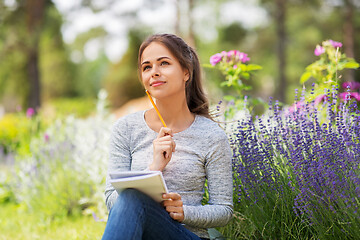 Image showing young woman writing to notebook at summer garden