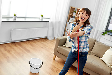 Image showing asian woman or housewife with mop singing at home