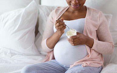 Image showing pregnant woman eating yogurt for breakfast in bed