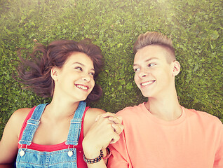 Image showing happy teenage couple lying on grass at summer