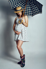 Image showing Pregnant woman in country style summer dress and straw hat standing under umbrella