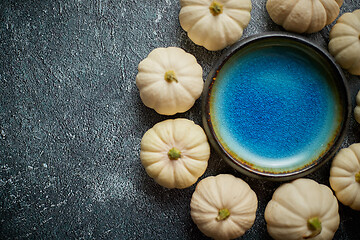 Image showing Cute white Baby boo mini pumpkins placed in circle with blue ceramic bowl in the middle