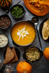 Image showing Delicious pumpkin soup with cream, seeds, bread and fresh herbs 