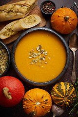 Image showing Homemade vegetarian pumpkin cream soup served in ceramic bowl. Decorated with seeds