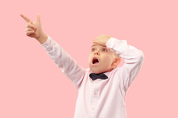 Image showing The young attractive teen boy looking suprised isolated on pink