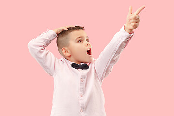 Image showing The young attractive teen boy looking suprised isolated on pink