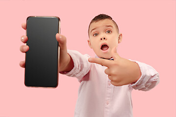 Image showing Indoor portrait of attractive young boy holding blank smartphone