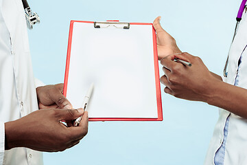 Image showing The female and male hands of afro american doctors on blue background