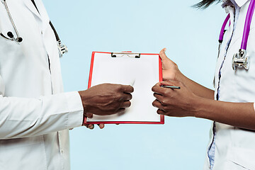 Image showing The female and male hands of afro american doctors on blue background