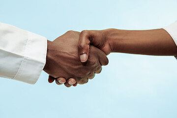 Image showing The female and male hands of afro american doctors on blue background