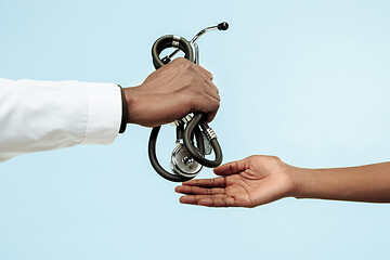 Image showing The female and male hands of afro american doctors on blue background