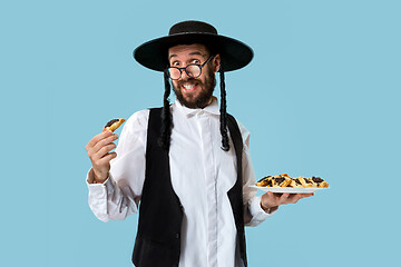 Image showing The young orthodox Jewish man with black hat with Hamantaschen cookies for Jewish festival of Purim