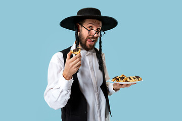 Image showing The young orthodox Jewish man with black hat with Hamantaschen cookies for Jewish festival of Purim