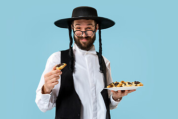 Image showing The young orthodox Jewish man with black hat with Hamantaschen cookies for Jewish festival of Purim