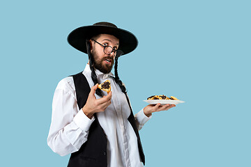 Image showing The young orthodox Jewish man with black hat with Hamantaschen cookies for Jewish festival of Purim