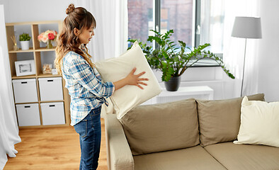 Image showing asian woman arranging sofa cushions at home