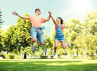 Image showing happy teenage couple jumping at summer park