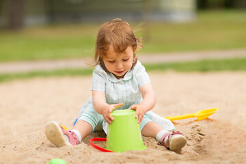 Image showing little baby girl plays with toys in sandbox