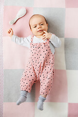 Image showing sweet baby girl in pink suit lying on blanket