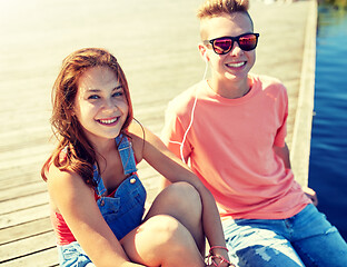 Image showing happy teenage couple with earphones on river berth