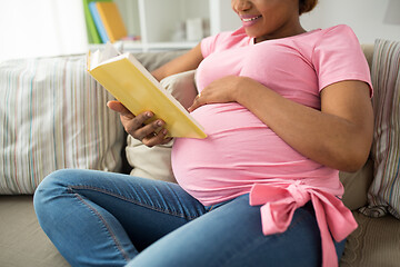 Image showing happy pregnant african woman reading book at home