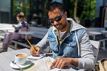 Image showing man with map and notebook at street cafe in city