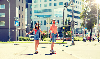 Image showing teenage couple riding skateboards on city street