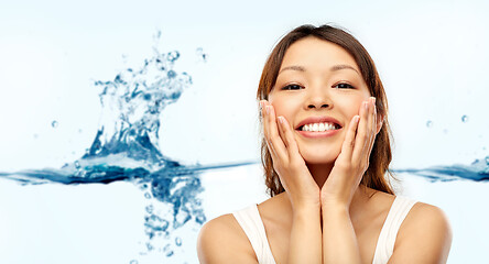 Image showing happy smiling young asian woman touching her face