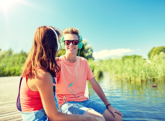 Image showing happy teenage couple with earphones on river berth