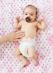 Image showing hand applying body lotion to baby girl\'s tummy