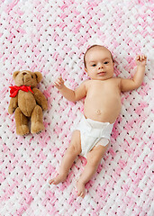 Image showing baby girl in diaper lying with teddy on blanket