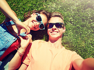 Image showing happy teenage couple taking selfie on summer grass