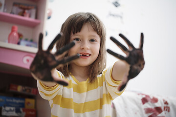 Image showing cute little girl at home painting with hands