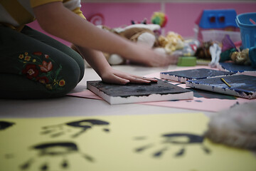 Image showing cute little girl at home painting with hands