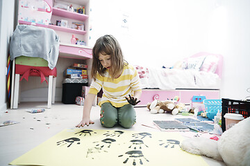 Image showing cute little girl at home painting with hands