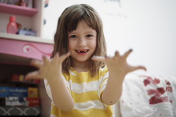 Image showing cute little girl at home painting with hands