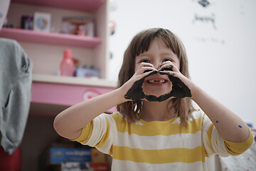 Image showing cute little girl at home painting with hands