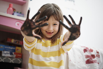 Image showing cute little girl at home painting with hands