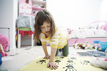 Image showing cute little girl at home painting with hands