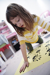 Image showing cute little girl at home painting with hands