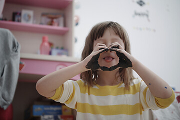 Image showing cute little girl at home painting with hands