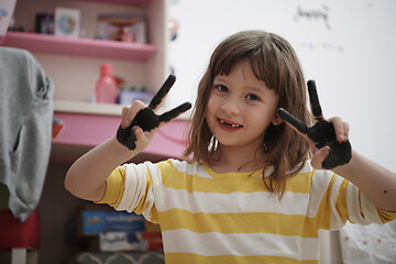 Image showing cute little girl at home painting with hands