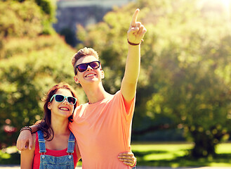 Image showing happy couple pointing finger at summer park