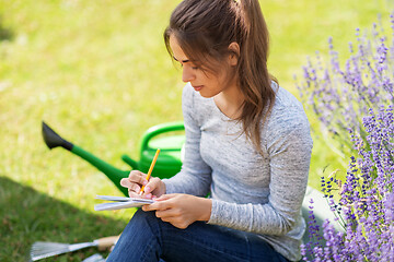 Image showing young woman writing to notebook at summer garden